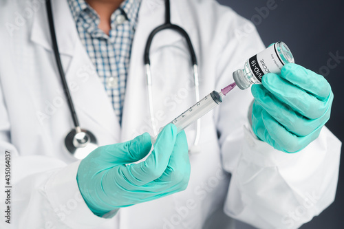 A doctor holding a syringe and COVID-19 vaccine bottle. Vaccine for immunization, and treatment from coronavirus infection. Close-up photo. Concept of medical and the fight against coronavirus