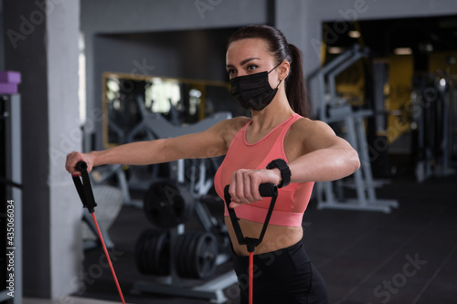 Sportswoman wearing medical face mask, working out at gym during pandemic