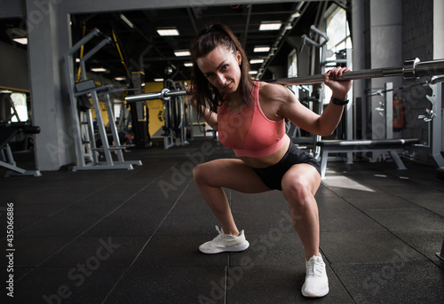 Full length shot of a fitness woman doing squats with barbell, copy space