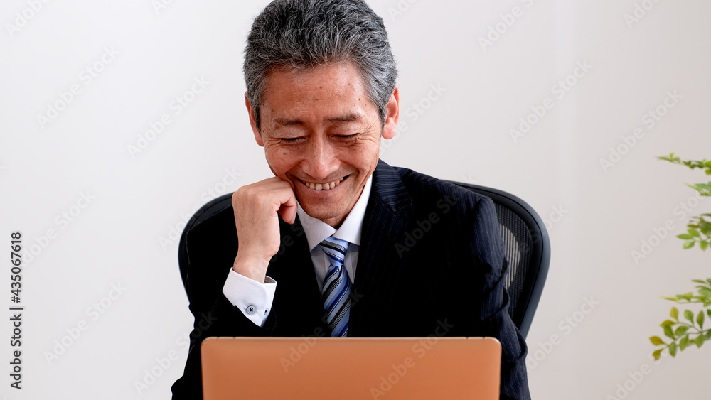 パソコンを打ちながら微笑むシニア社長