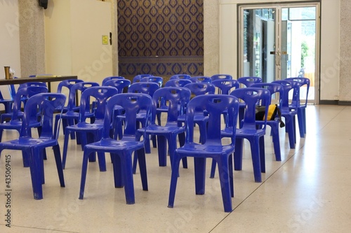 Numerous empty blue plastic chairs lined up in the conference room.