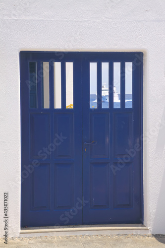 Wallpaper Mural View on isolated mediterranean blue wood door with white wall. Blurred ferry boat and sea in window background. Torontodigital.ca