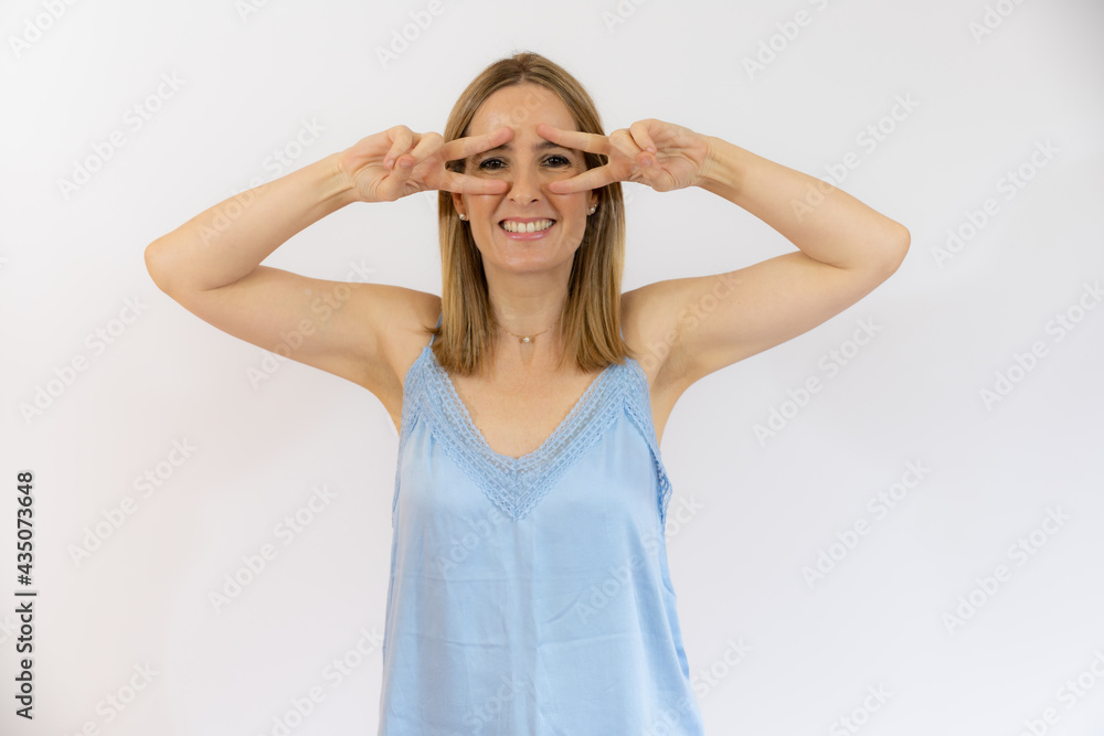 Image of happy young woman standing isolated over white background showing peace gesture. Looking camera.