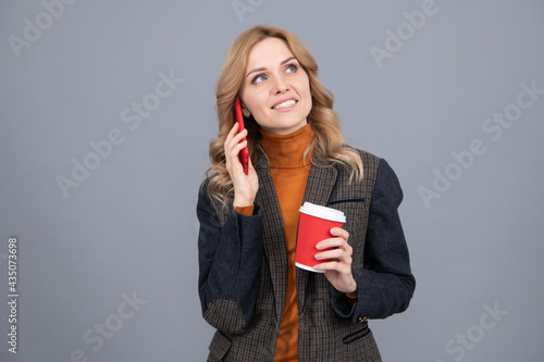 Chattering girl talk on mobile phone drinking coffee grey background, chatterbox photo