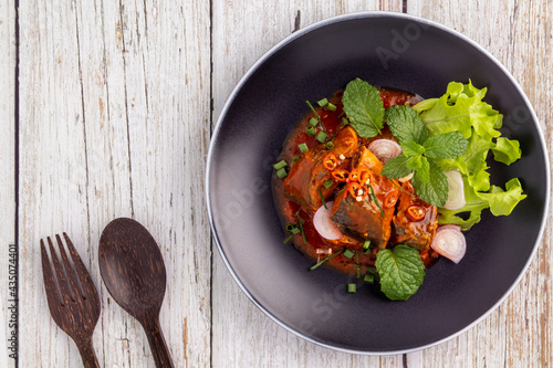 Photos Flat lay mackerel in tomato sauce, a hot and sour salad with vegetables and herbs served on a black plate