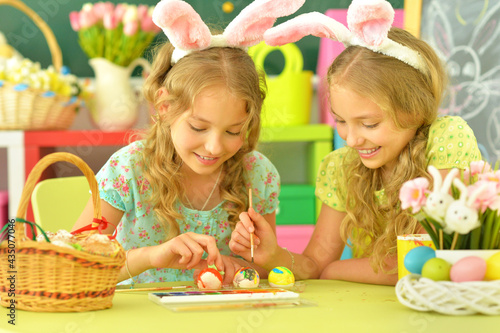 Cute twins wearing rabbit ears decorating Easter eggs