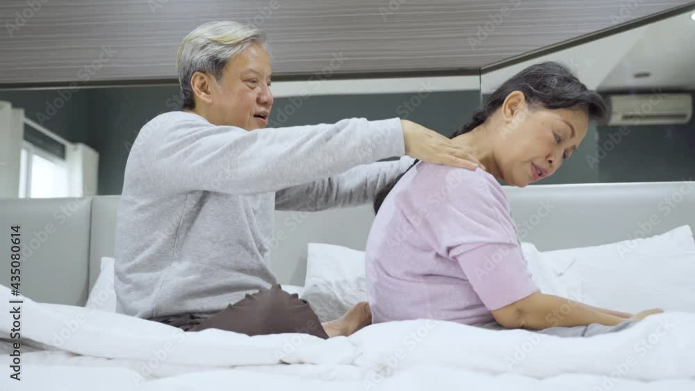 Elderly man massaging backbone of his wife on bed Elderly man massaging backbone of his wife on bed