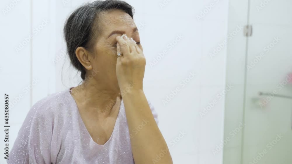 Elderly woman cleaning her face with cotton pads Elderly woman cleaning her face with cotton pads