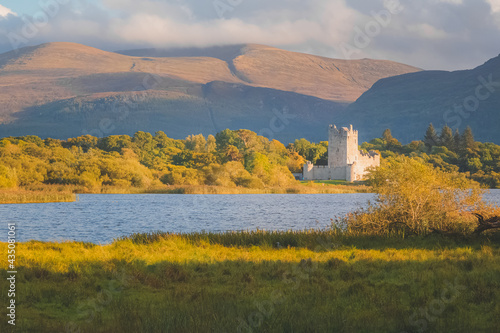 Golden hour sunset light on scenic mountain landscape of the historic medieval Ross Castle on Lough Leane lake in Killarney National Park, County Kerry, Ireland. photo