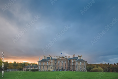 A dark, moody ominous sunset sky over the historic Dalkeith Palace manor in Dalkeith Country Park, Edinburgh, Scotland.