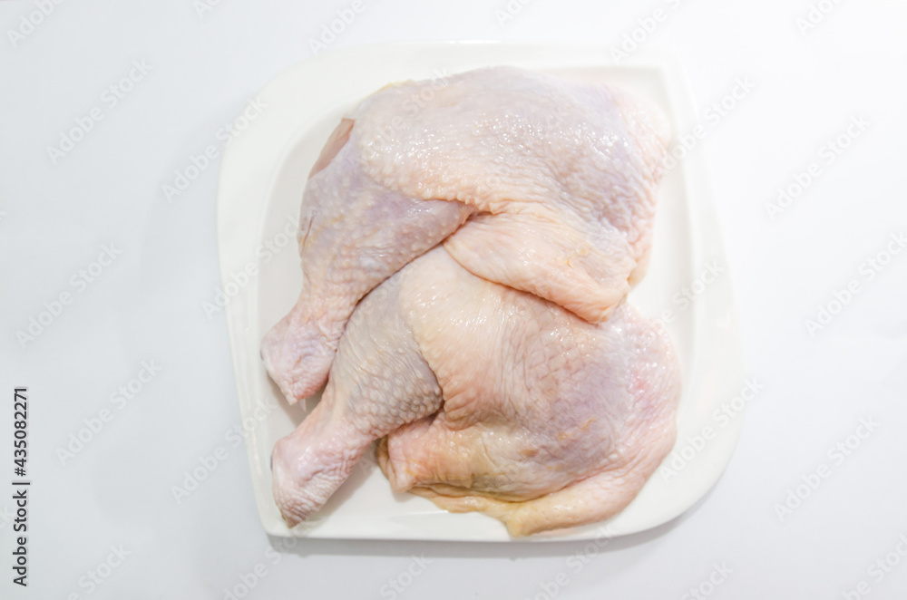Fresh chicken thighs on a white plate on a white background