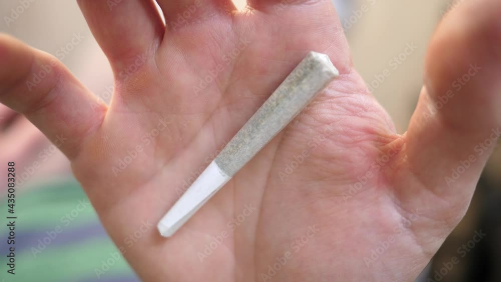 Hand opening showing a cannabis joint in the palm of the hand. Closeup Hand opening showing a cannabis joint in the palm of the hand. Closeup