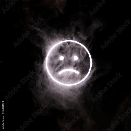 Stylized face expressing emotion glows through the stream of smoke in the dark