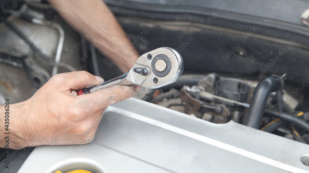 Mechanic repairing car with ratchet wrench. Mechanic repairing car with ratchet wrench.