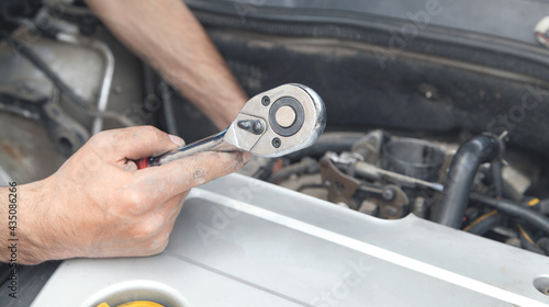 Mechanic repairing car with ratchet wrench. © andranik123