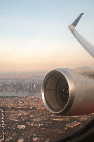 sunset view of airplane wing and jet engine with Manhattan island in the background 