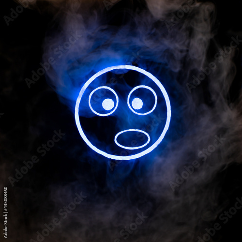 Stylized face expressing emotion glows through the stream of smoke in the dark