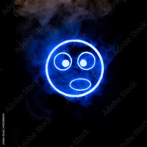 Stylized face expressing emotion glows through the stream of smoke in the dark