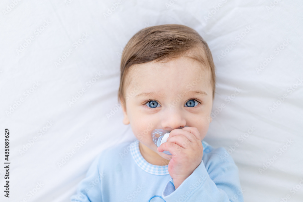 baby boy with pacifier on bed before going to bed in blue bodysuit, happy healthy little baby baby boy with pacifier on bed before going to bed in blue bodysuit, happy healthy little baby