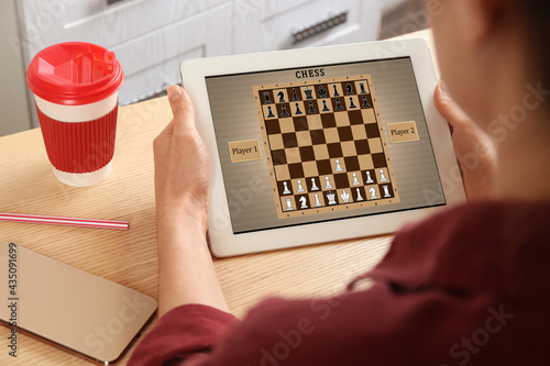 Woman playing online chess on tablet indoors, closeup
