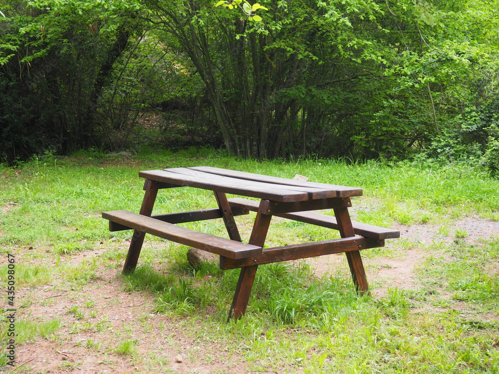 bonito y agradable rincón para hacer un picnic formado por una mesa de madera, una fuente al fondo y rodeado de naturaleza, en prades, tarragona, españa, europa