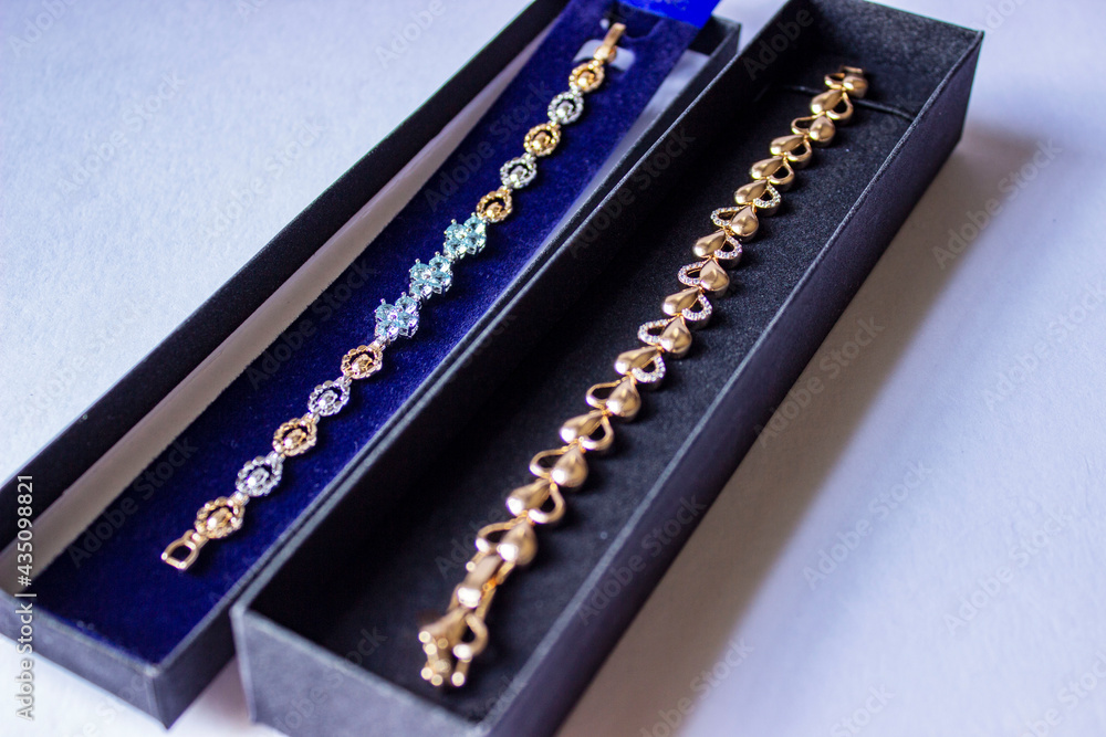 Wedding rings in an elegant red box in the warm sunlight on a table with jewelry set in the background. Gold rings in a scene with vibrant colors. Wedding rings in an elegant red box in the warm sunlight on a table with jewelry set in the background. Gold rings in a scene with vibrant colors.