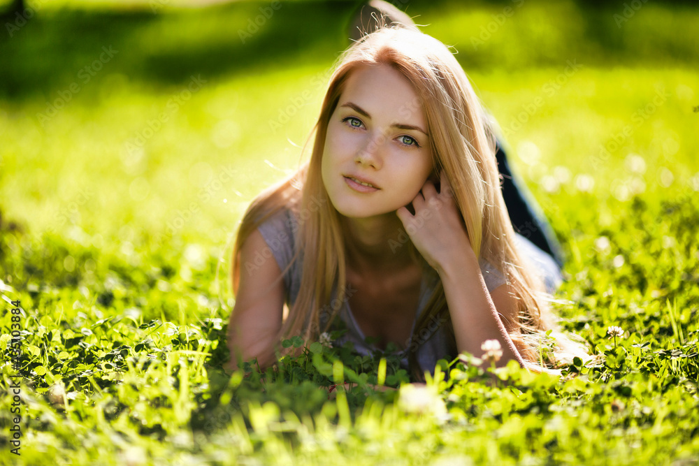 A beautiful girl lies in the park on the grass and dreamily looks around A beautiful girl lies in the park on the grass and dreamily looks around