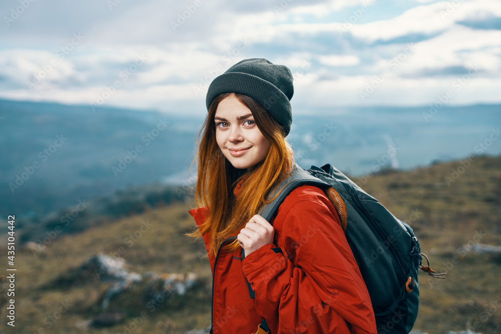 portrait of a traveler In a red jacket and hat and with a backpack outdoors in the mountains fresh air