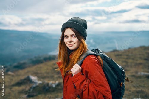 portrait of a traveler In a red jacket and hat and with a backpack outdoors in the mountains fresh air © SHOTPRIME STUDIO