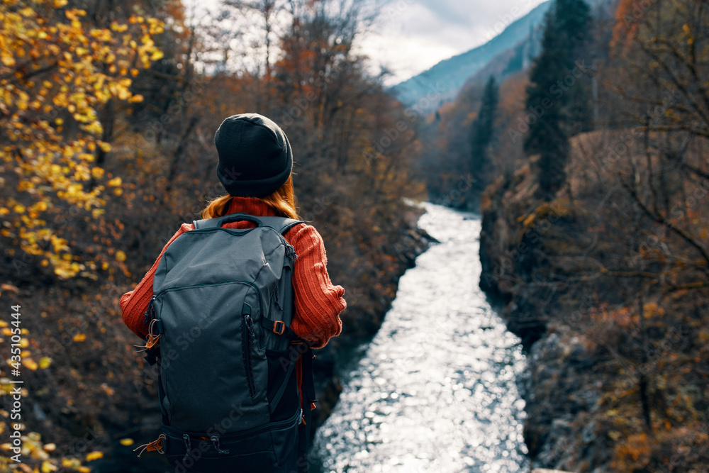 woman tourist with backpack admires nature river mountains travel