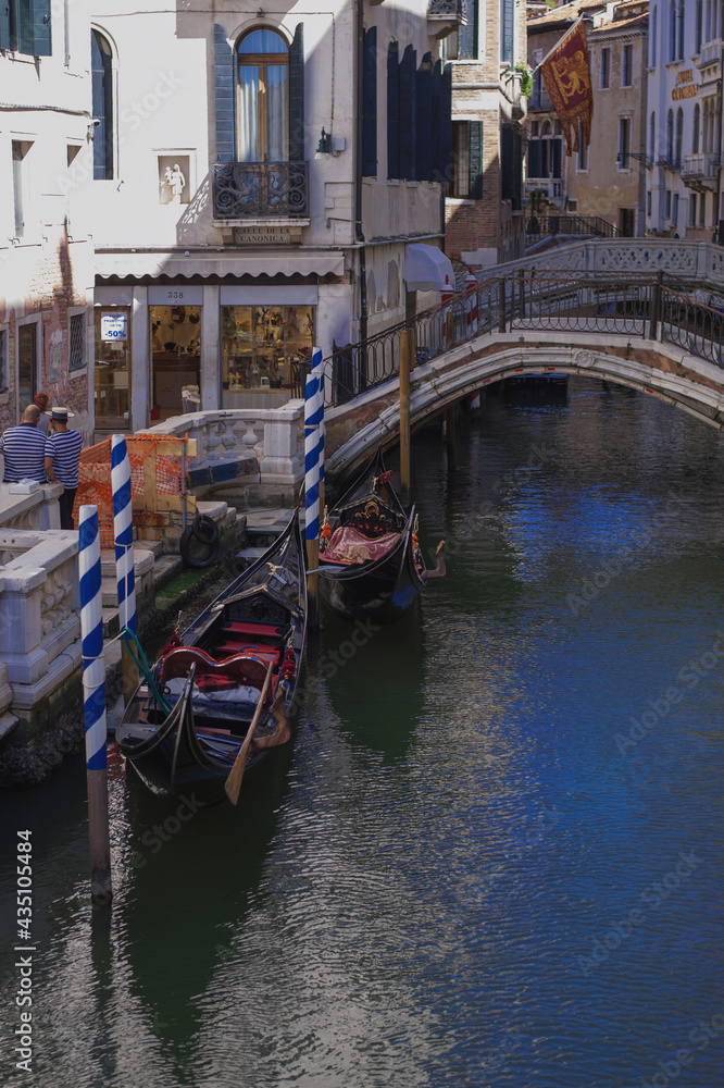 gondolas moored by the canal facing facade of the narrow streets of the old city of Venice