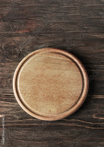 Vintage oak empty circle pizza board on wooden textured table. Background for menu page. Retro style filtered photo