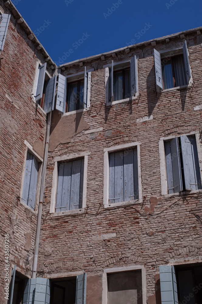 facades with blue wooden shutters of the narrow streets of the old city of Venice