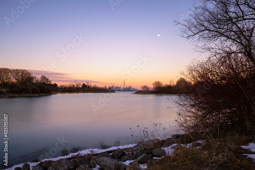 Beautiful dusk colors over Humber Bay  with the full moon rising over the Toronto skyline .