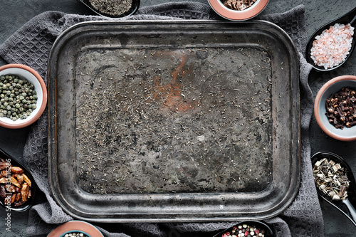 Various spices in ceramic oriental spoons and pinch bowls on dark grey. Textile towel on textured background. Flat lay with copy-space on tray. Various dry herbs, pepper, smoked salt, chili, thyme.