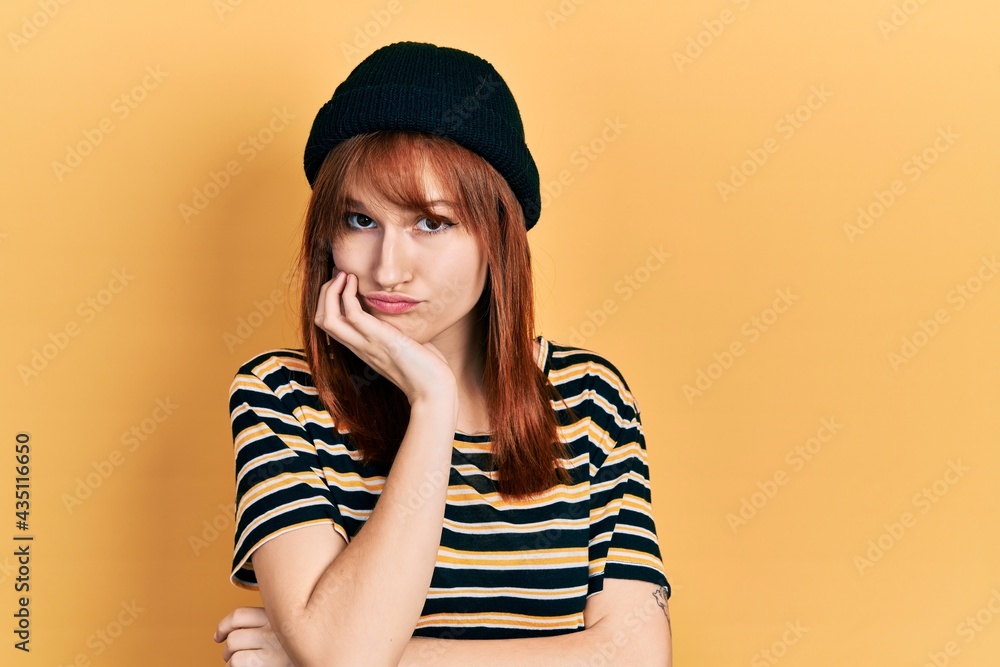 Redhead young woman wearing wool cap thinking looking tired and bored with depression problems with crossed arms. Redhead young woman wearing wool cap thinking looking tired and bored with depression problems with crossed arms.