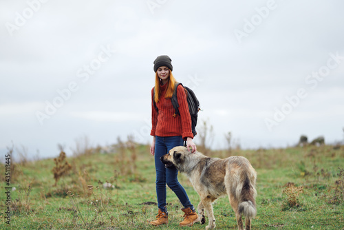 woman hiker with a backpack in nature walks the dog in the mountains friendship travel
