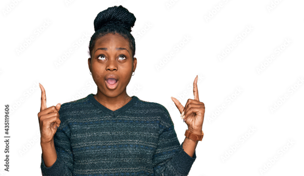 Young african american woman wearing casual clothes amazed and surprised looking up and pointing with fingers and raised arms.