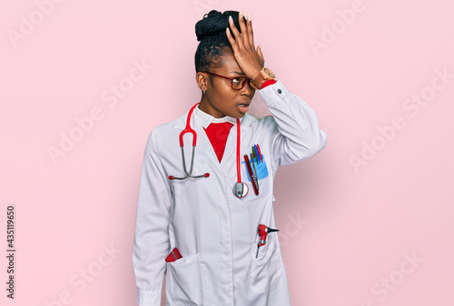 Young african american woman wearing doctor uniform and stethoscope surprised with hand on head for mistake, remember error. forgot, bad memory concept.