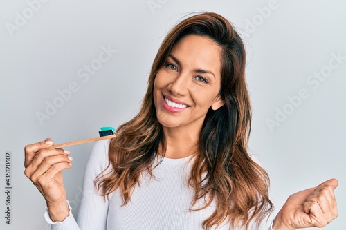 Wallpaper Mural Young latin woman holding toothbrush with toothpaste screaming proud, celebrating victory and success very excited with raised arm Torontodigital.ca