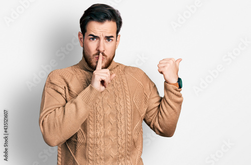 Young hispanic man wearing casual clothes asking to be quiet with finger on lips pointing with hand to the side. silence and secret concept.