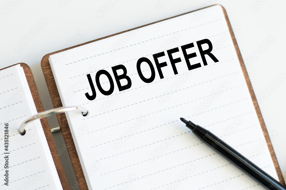 Motivational words: JOB OFFER on the notebook next to a black marker. Business and finance concept Motivational words: JOB OFFER on the notebook next to a black marker. Business and finance concept