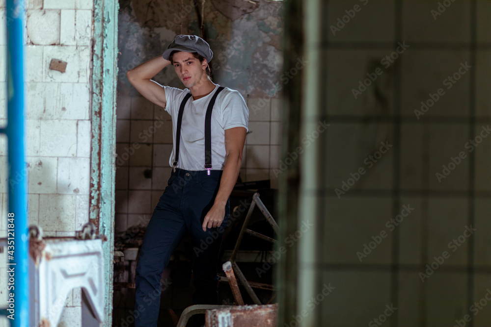 Joven en construcción abandonada vestido con gorro tiradores y camiseta Joven en construcción abandonada vestido con gorro tiradores y camiseta