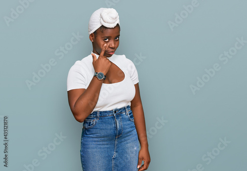 Young african woman with turban wearing hair turban over isolated background pointing to the eye watching you gesture, suspicious expression