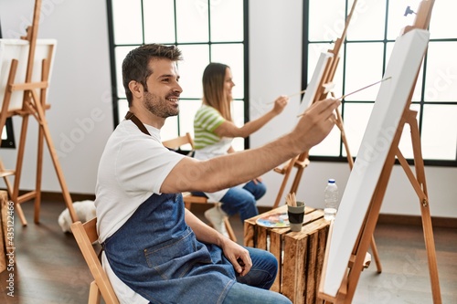Two hispanic students smiling happy painting at art studio