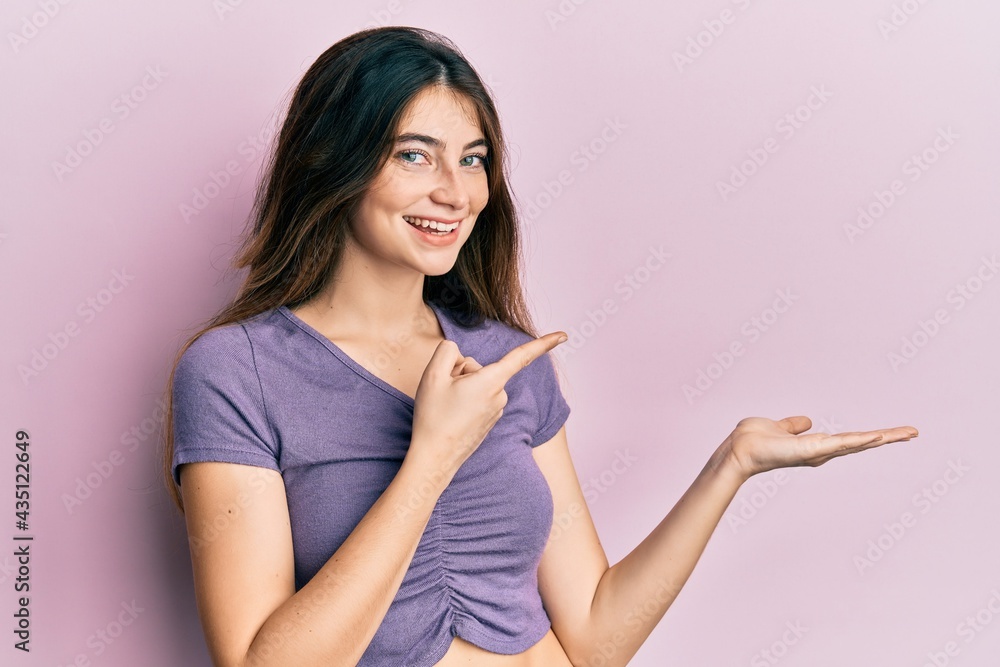 Young caucasian woman wearing casual clothes amazed and smiling to the camera while presenting with hand and pointing with finger. Young caucasian woman wearing casual clothes amazed and smiling to the camera while presenting with hand and pointing with finger.