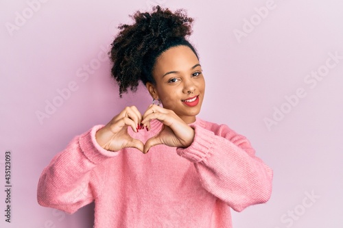 Young african american girl wearing casual clothes smiling in love doing heart symbol shape with hands. romantic concept.