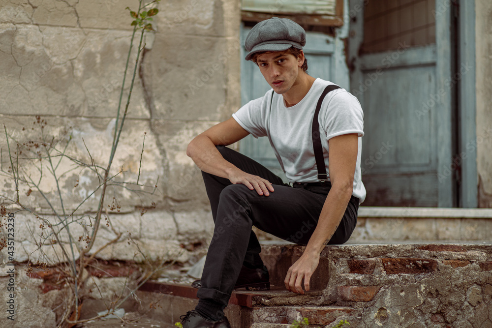 Joven en construcción abandonada vestido con gorro tiradores y camiseta Joven en construcción abandonada vestido con gorro tiradores y camiseta