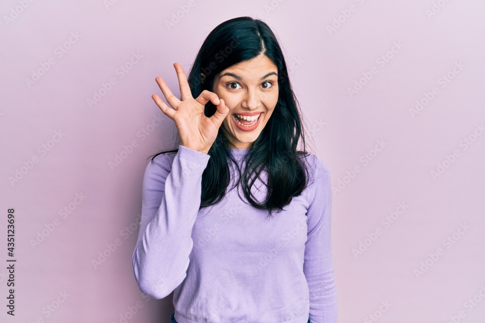 Young hispanic woman wearing casual clothes smiling positive doing ok sign with hand and fingers. successful expression. Young hispanic woman wearing casual clothes smiling positive doing ok sign with hand and fingers. successful expression.