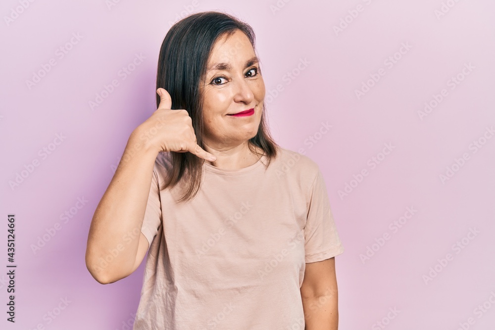 Middle age hispanic woman wearing casual clothes smiling doing phone gesture with hand and fingers like talking on the telephone. communicating concepts. Middle age hispanic woman wearing casual clothes smiling doing phone gesture with hand and fingers like talking on the telephone. communicating concepts.